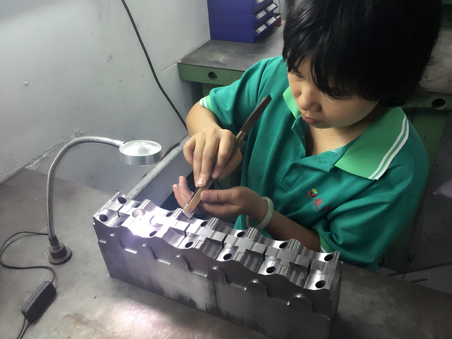 省模師傅正在用砂紙對(duì)模具進(jìn)行省模工序，需確保去除火花紋、打磨平整、光潔度達(dá)到一定要求才能進(jìn)下工序：拋光